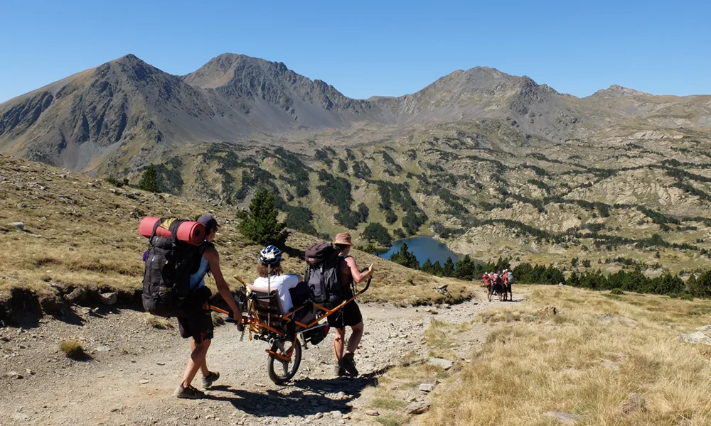 Randonneurs transportant un fauteuil tout-terrain en montagne
