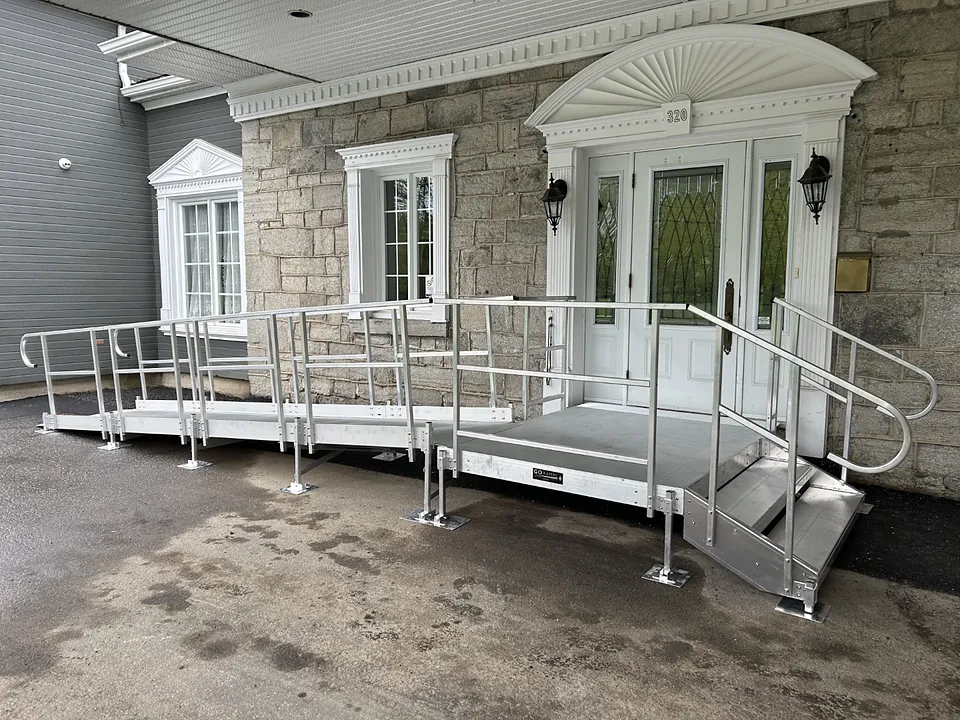 Rampe et palier en aluminium devant l’entrée d’une maison en pierre