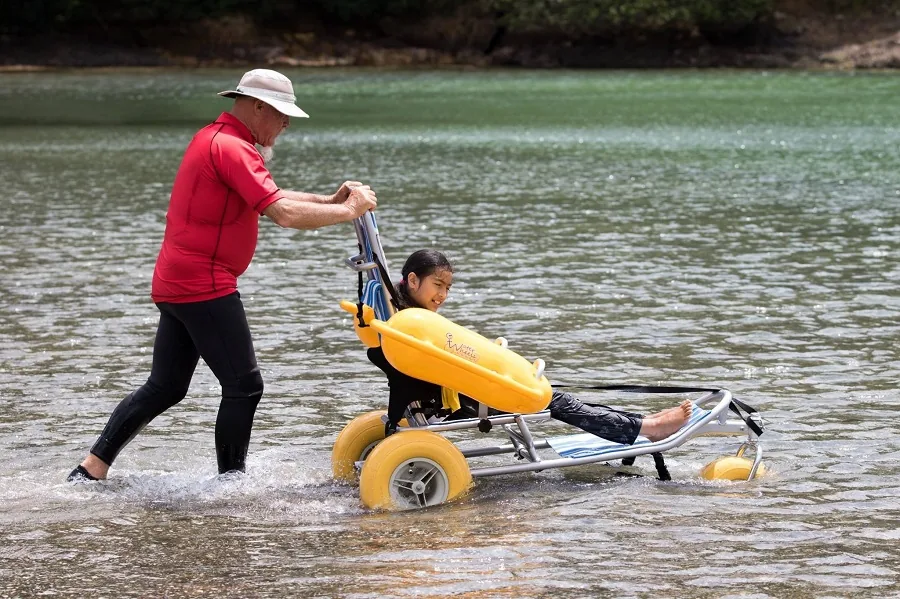 Fauteuil WATERWHEELS dans l’eau, accompagné d’un proche